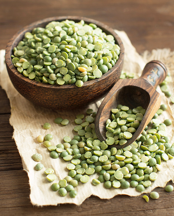 Uncooked Green Split Peas in a bowl with a spoon